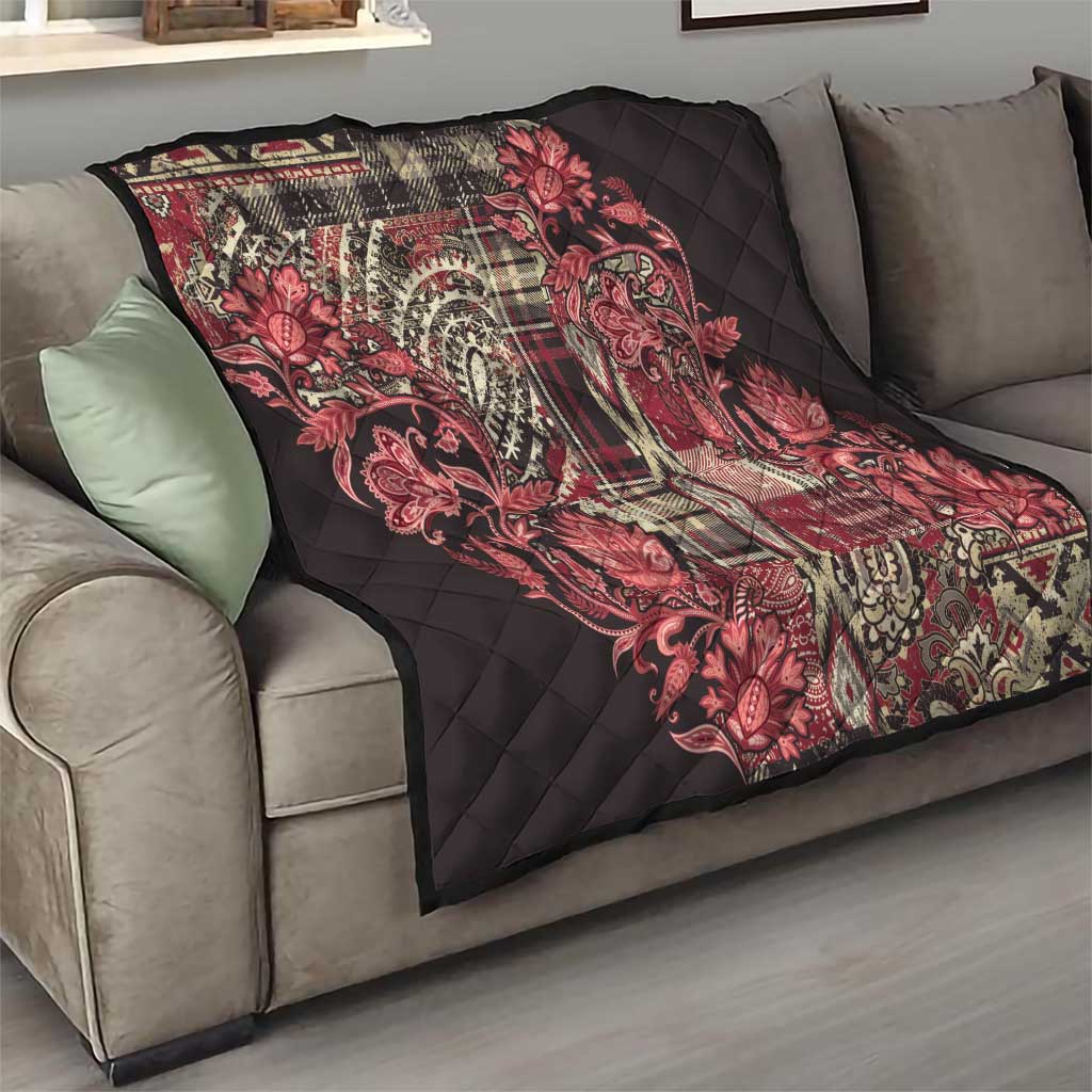 Red paisley floral quilt draped on a gray sofa, quilted black surface