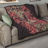 Red paisley floral quilt draped on a gray sofa, quilted black surface