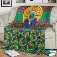 Green African pattern throw blanket on a sofa with colorful tribal border and central emblem