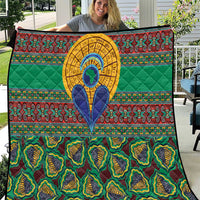 Green kanga-style quilt with colorful border patterns and central blue-and-yellow shield motif
