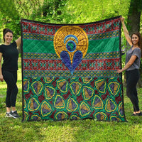 Green traditional kanga-style quilt with geometric bands, central blue figure, and patterned bottom