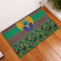 Green rubber doormat in doorway, colorful kanga pattern with yellow circular heart motif