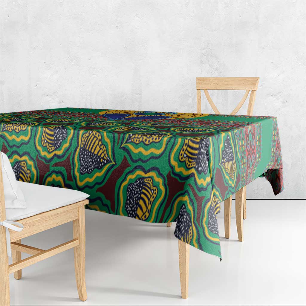 Green African pattern tablecloth hanging over table edge with multicolor motifs