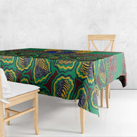 Green African pattern tablecloth hanging over table edge with multicolor motifs