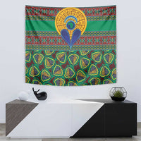 Green traditional kanga tapestry with central bird-like emblem and colorful striped band