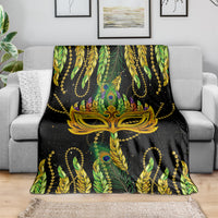 Feather mask Mardi Gras blanket in green and black with gold leaf details, on bed