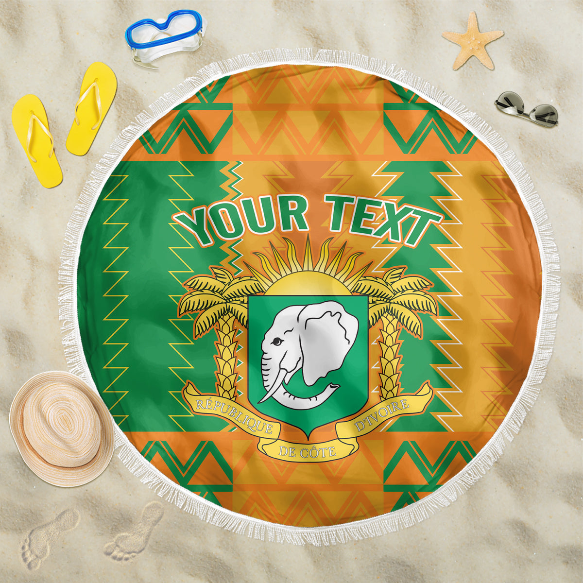 Round beach blanket with green and orange pattern, 'YOUR TEXT' and elephant crest, fringe