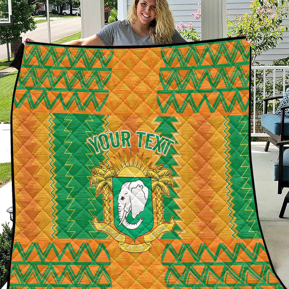 Football quilt in orange and green zigzag with elephant crest, held up by model