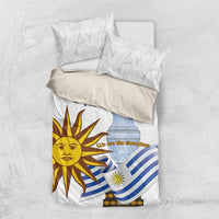 White bedding set laid flat, featuring blue striped flag and sun face on duvet cover
