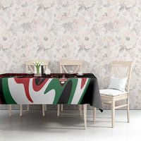Black, red, green, and white tablecloth with large tribal graphic motif over dining table