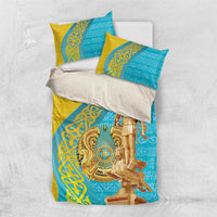 Gold and teal bedding set laid flat with pillows and gold statue artwork