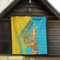 Gold and blue quilt displayed on a wall or porch, with gold statue motif.