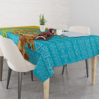 Turquoise tablecloth with repeating pattern and gold trim over table