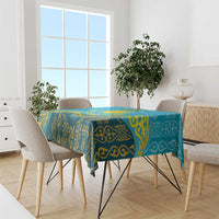 Blue and teal tablecloth with gold ornamental pattern draped over dining table