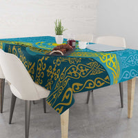 Blue tablecloth with gold swirl pattern and teal border over rectangular dining table