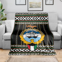 Black emblem graphic blanket with geometric trim and multicolor striped bands.