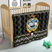 Personalized quilt on wooden baby bed, black base with central emblem and geometric trim