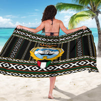 Black sarong laid out wide with repeating geometric stripes and central crest emblem