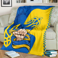 Draped blue and yellow blanket with trident emblem and clasped hands graphic