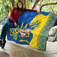 Personalized quilt draped over couch: blue and yellow Ukrainian design with trident and hands
