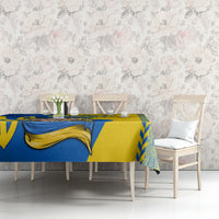 Square tablecloth with blue-and-gold folk pattern across tabletop and matching border
