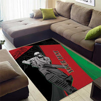 Black area rug with bold red and green stripes and cricketer design, Arabic script