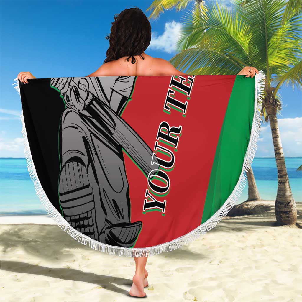 Person holds round fringe beach blanket showing cricket player art on red, green, and black