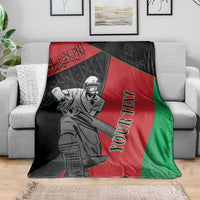 Afghanistan cricket blanket on sofa, showing cricket player and red-green-black stripes