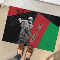 Cricket rubber doormat with custom text, black red green player graphic, feet visible nearby