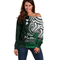 Women's off-shoulder green sweater with white tribal scroll graphic and heart accents