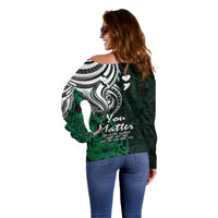 Women's off-shoulder green sweater back/side view with white tribal scroll pattern