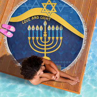 Blue round Hanukkah beach blanket with yellow Star of David, menorah, and “Love and Light”