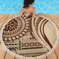Round beach blanket with brown geometric design and white fringe on wooden deck