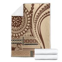 Folded brown and cream geometric art blanket with circular medallion, stacked with white towels