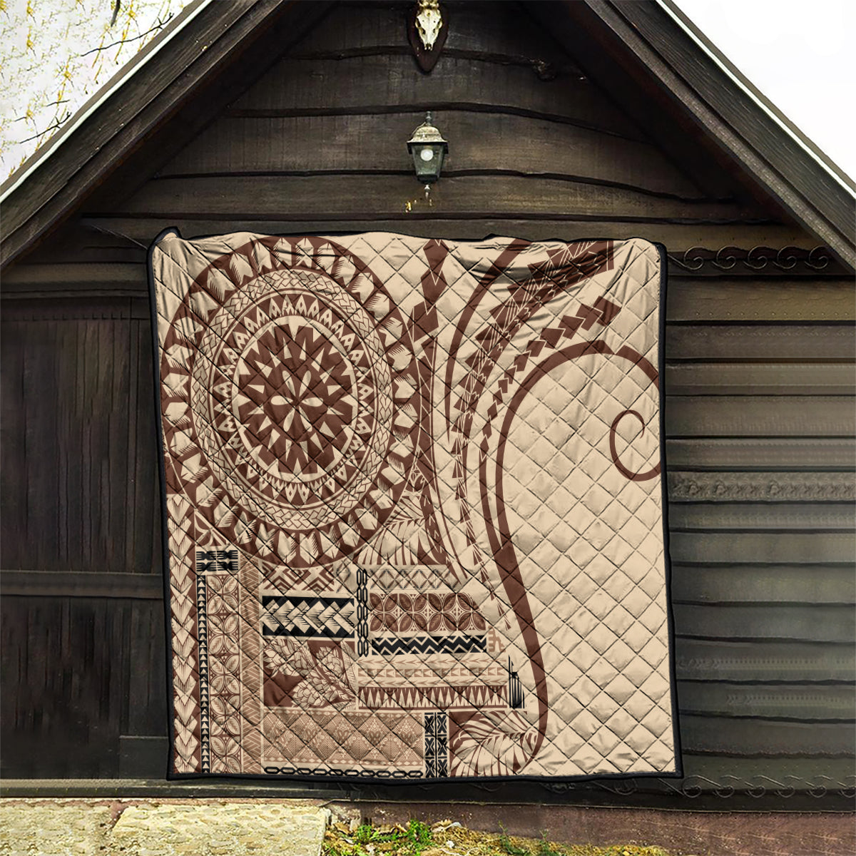 Brown Samoa Siapo-style quilt with sun medallion and diamond patterns, displayed in alcove