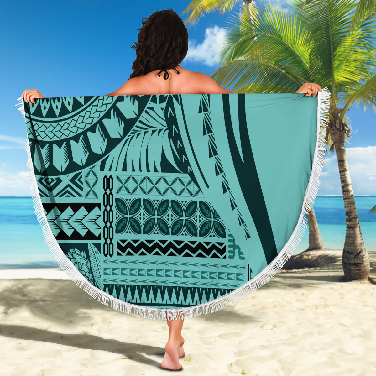 Round turquoise patterned beach blanket with white fringe, held stretched