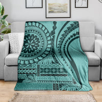 Turquoise geometric siapo-style throw blanket draped over sofa, bold black patterns