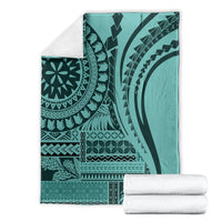 Turquoise patterned blanket folded, black mandala and tribal-style stripe designs