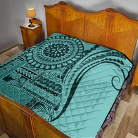 Turquoise quilt with central mandala and geometric bands, quilted surface, on bed