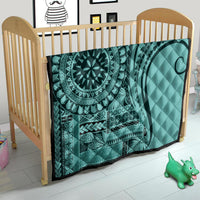 Turquoise quilt in a crib, quilted with mandala medallion and tribal stripe panel
