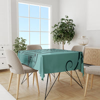 Turquoise patterned tablecloth with leaf swirl motif and geometric border on dining table