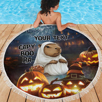 Round black Halloween beach blanket with capybara in white ghost wrap, pumpkins, 'YOUR TEXT', fringe.
