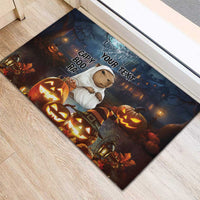 Halloween rubber doormat on wood floor, capybara ghost among jack-o'-lanterns and lanterns.