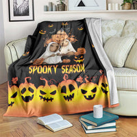 Spooky season blanket, black with orange gradient and smiling skull faces and pumpkins