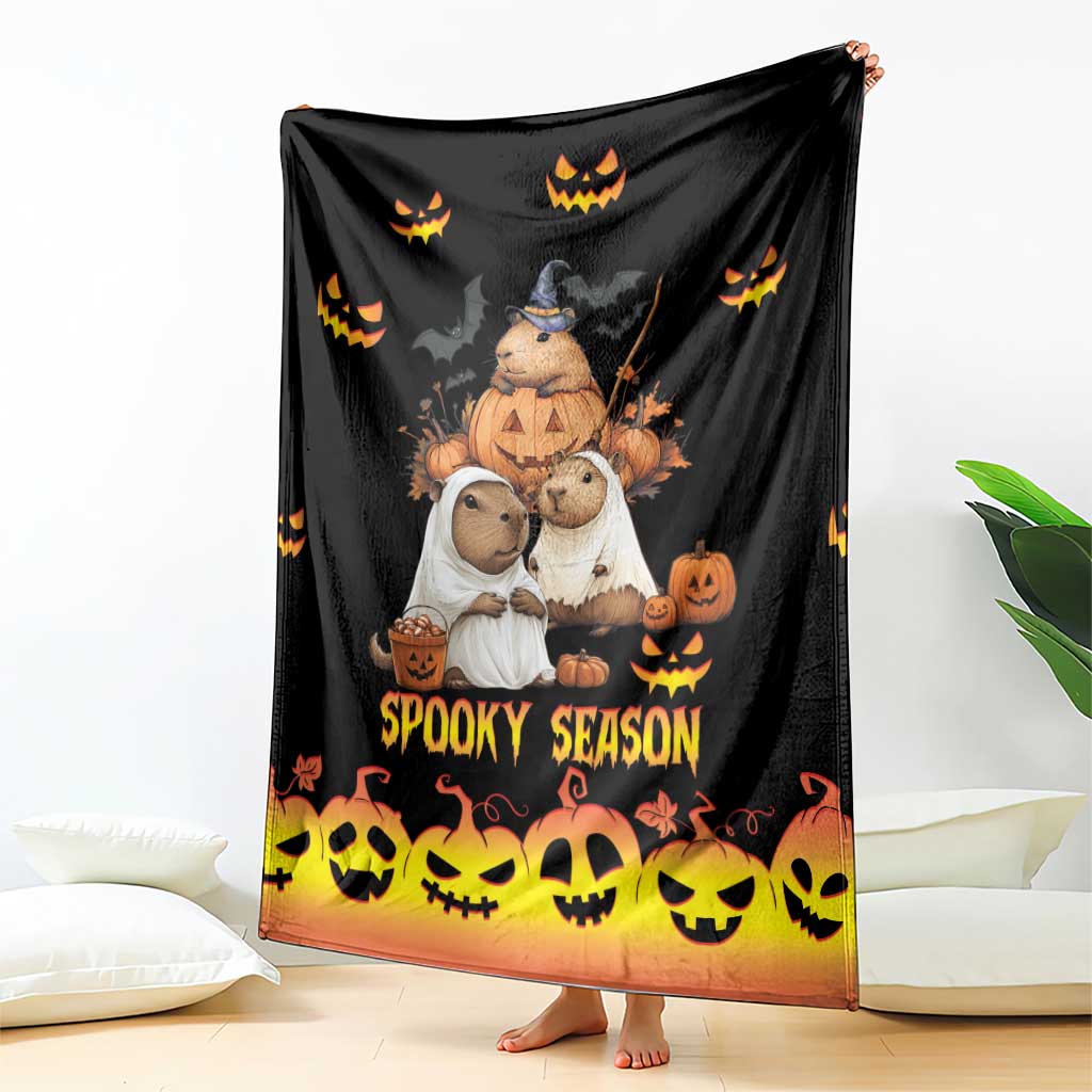 Spooky season blanket draped on the floor, black with orange glow and jack-o’-lantern graphics