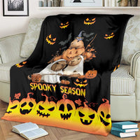 Spooky season blanket on a couch, black with orange-bottom gradient and cute animal pumpkin scene