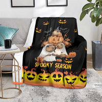 Spooky season blanket on a gray loveseat, black with orange fade and yellow skull border