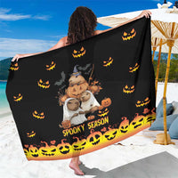 Black spooky season sarong with cartoon pumpkins, ghosts, and jack-o-lantern border
