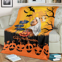 Orange Halloween capybara ghost throw blanket on sofa with bats, tree branches, and trick-or-treat sign