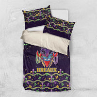 Purple duvet and two pillowcases in flat lay, with carnival mask design and fleur-de-lis border